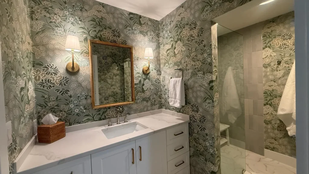 View of bathroom with wallpaper and brass accents
