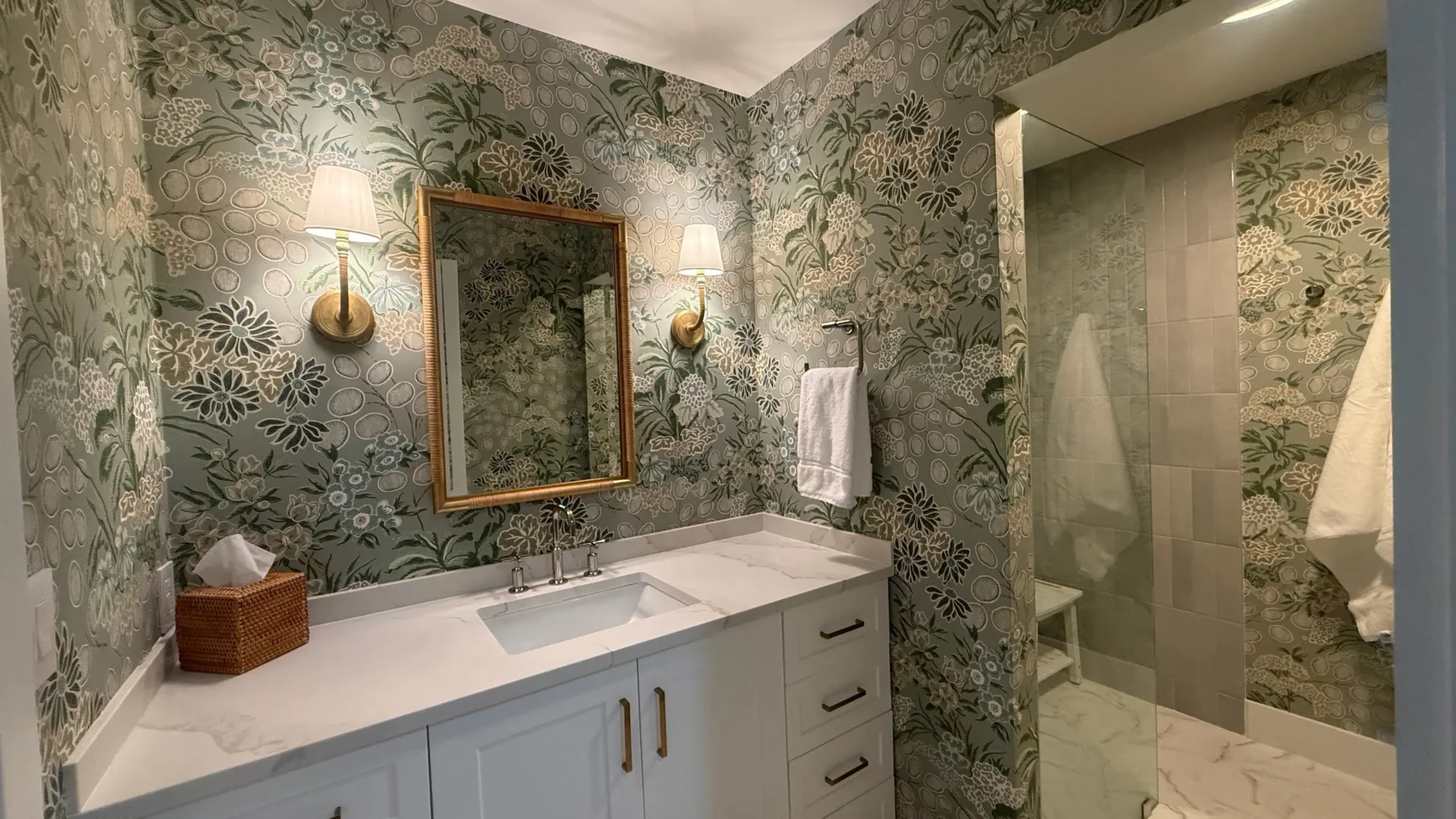 View of bathroom with wallpaper and brass accents